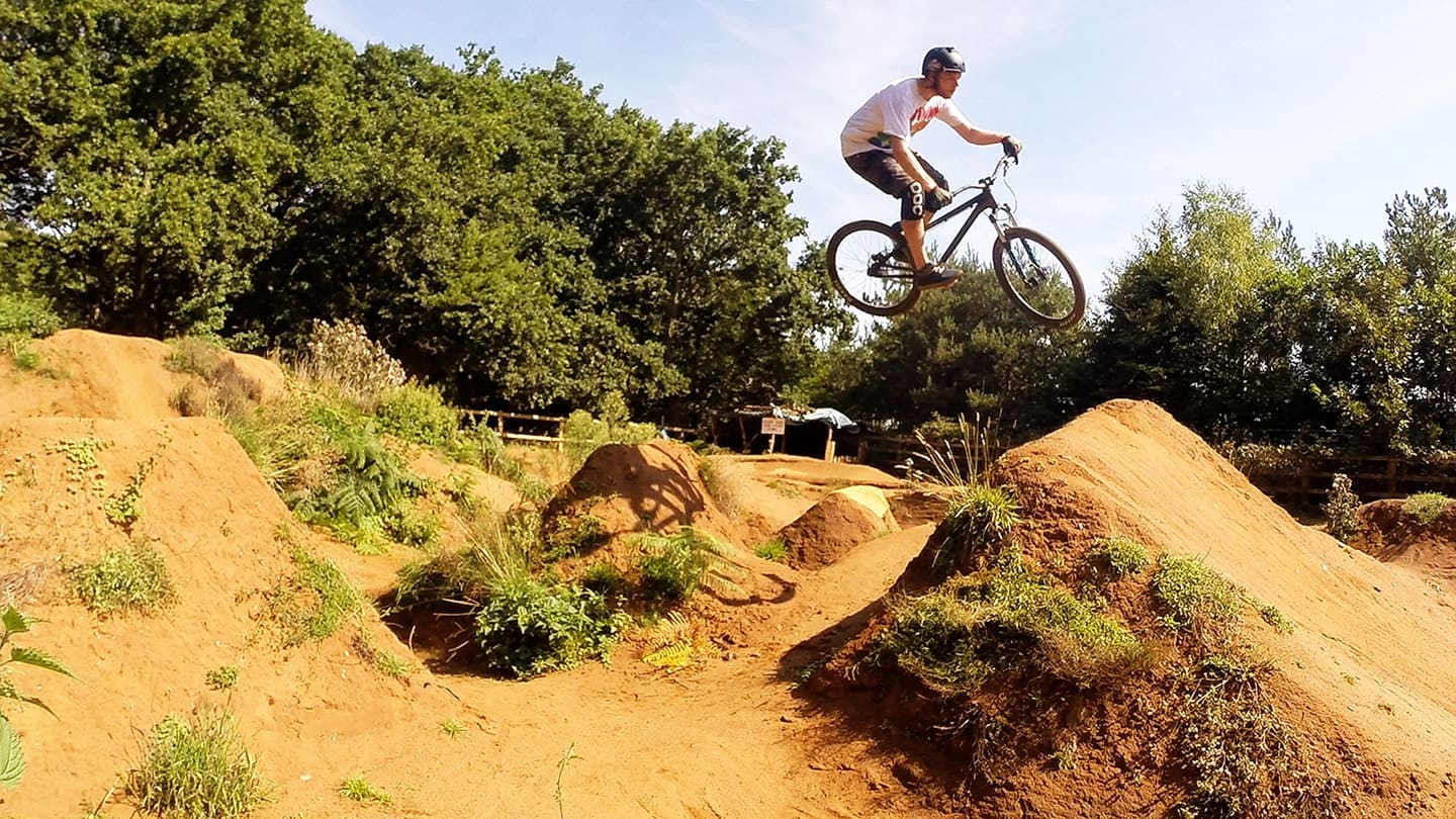 A mountain biker airborne over a dirt jump line