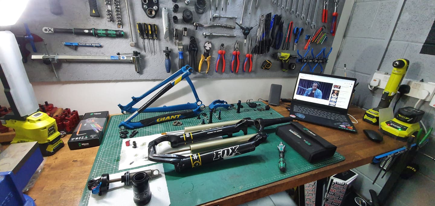 A suspension fork and shock stripped down on the workbench for servicing